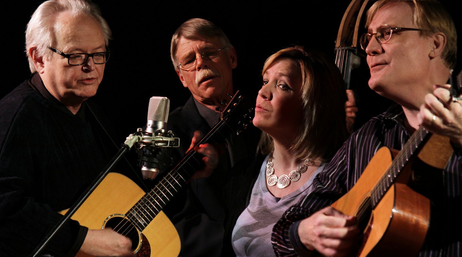 East of Westreville: Boyd Bristow, Al Slaathaug, Kaija Bonde, and Brian Bonde gathered around a single microphone