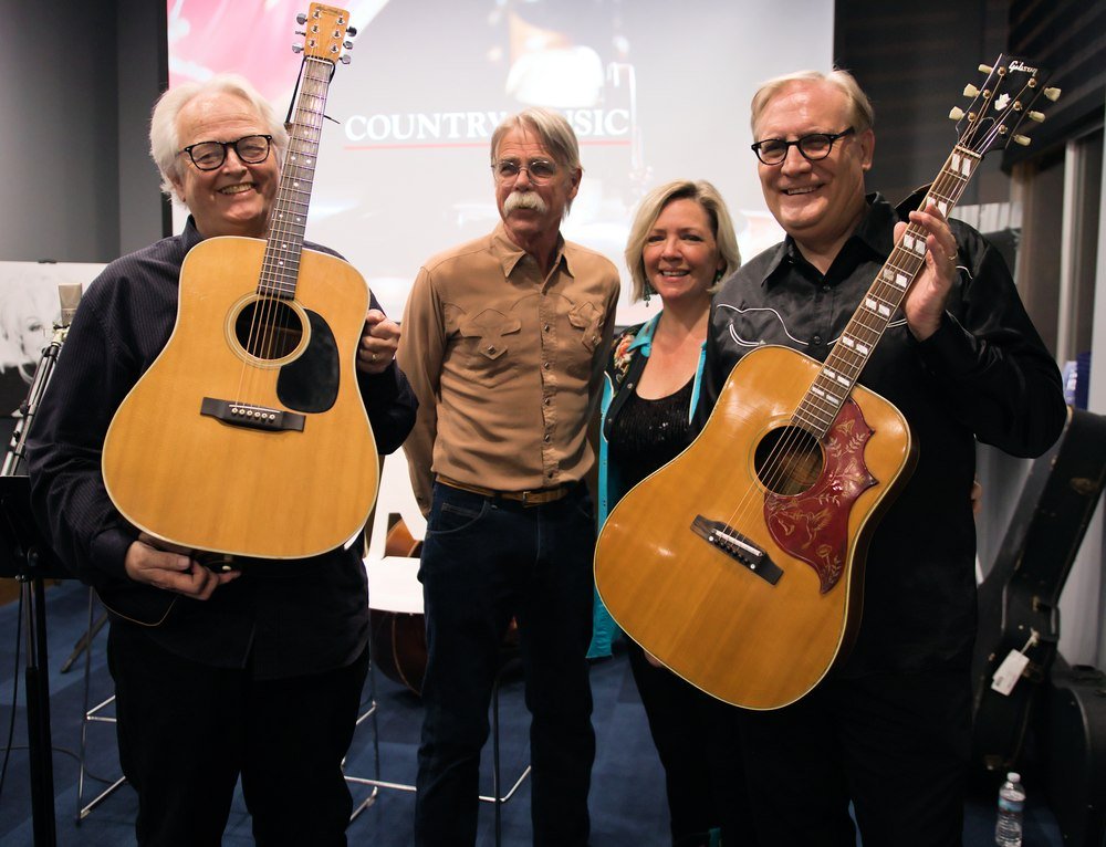 Boyd, Al, Kaija, and Brian holding Johnny Cash's and June Carter Cash's guitars while filming a Public Broadcasting special