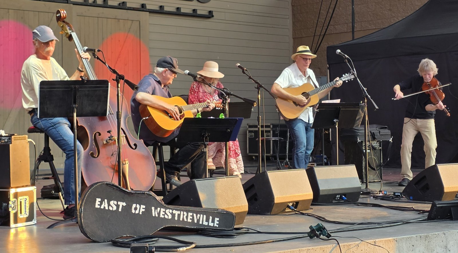 East of Westreville on stage at Levitt at the Falls, July 3, 2026, with the stenciled band guitar case at the front of the stage