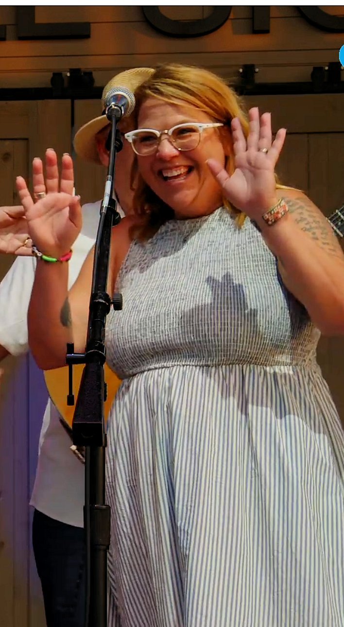 Suzannah Chap at the microphone, all smiles, sitting in with the band
